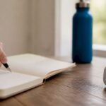 Hand writing GED essay draft with timer nearby